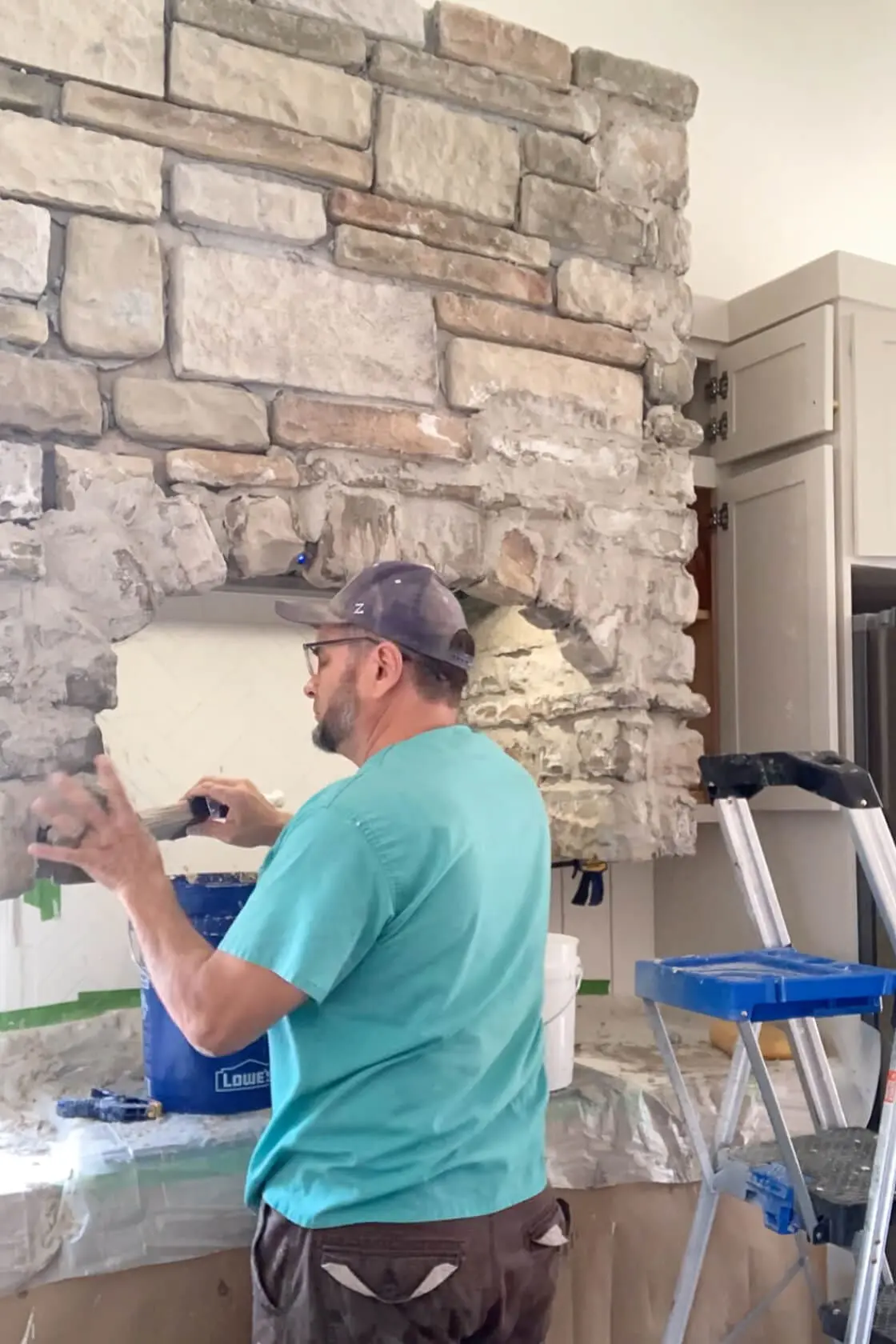 Using a masonry brush to smooth out mortar on DIY stone range hood.